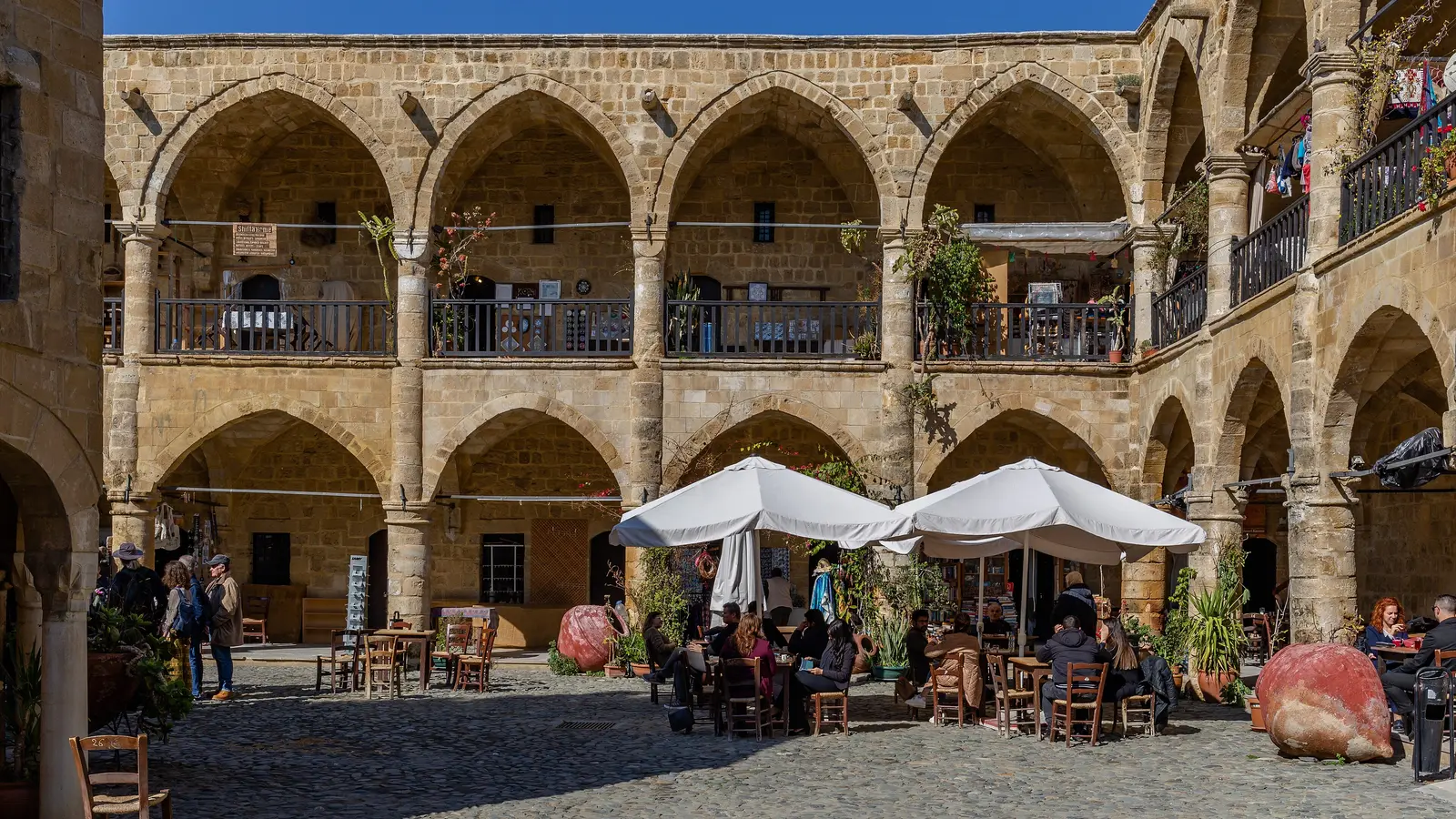 Lefkoşa'daki Büyük Han'ın iki katlı kemerli revakları ve avludaki kafe masaları